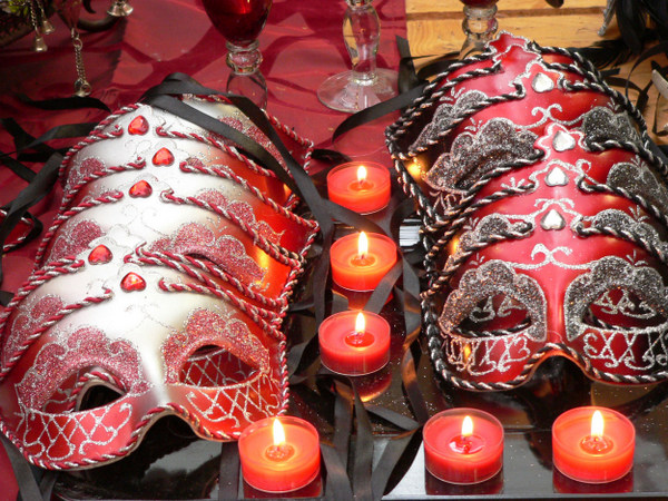 Schnell gemacht ist diese Karnevalsdekoration: Mit venezianischen Masken dekorierte Kerzengläser werden durch leuchtende Teelichte in RAL-Qualität perfekt in Szene gesetzt.  Foto: Gütegemeinschaft Kerzen. 